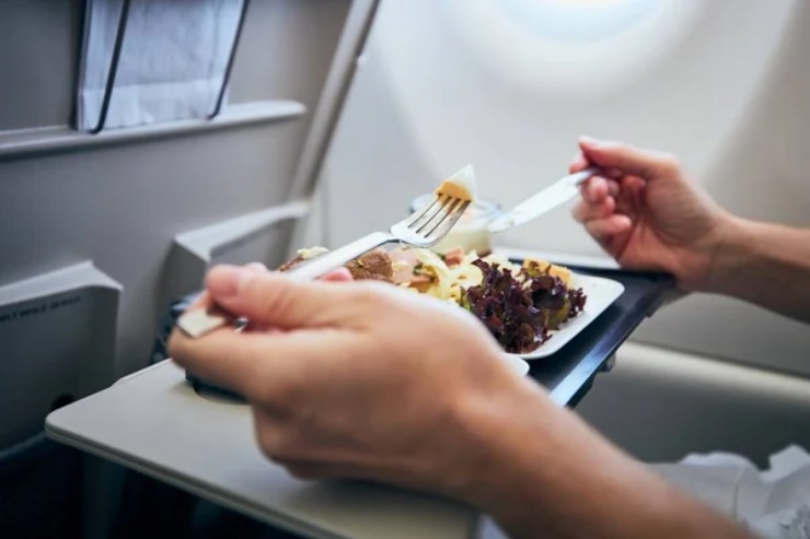 Una persona mentre mangia durante il viaggio (Depositphotos)